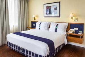 a hotel room with a large bed and a phone at Holiday Inn Lisbon by IHG in Lisbon