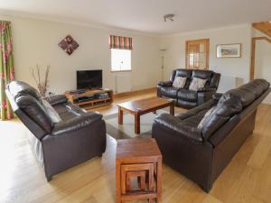 a living room with leather furniture and a flat screen tv at Muir Iosal in Clunie