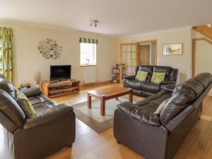 a living room with leather furniture and a flat screen tv at Lon Cottage in Clunie