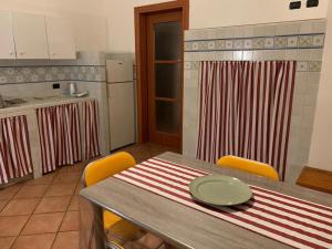 eine Küche mit einem Tisch mit gelben Stühlen und einer Küche mit einer Theke in der Unterkunft Tra monti, trulli e mare - Cisternino Valle Itria in Cisternino