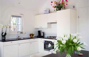 a white kitchen with white cabinets and flowers in a vase at Het Polderhuisje in Strijen