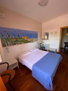 una camera da letto con un grande letto bianco e un dipinto sul muro di Ferrari a Goro