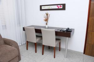 a dining room table with two white chairs and a desk at San Diego Lancaster Teófilo Otoni in Teófilo Otoni