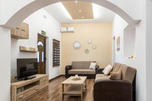 a living room with a couch and a tv at Kolymbia memories house in Kolymbia