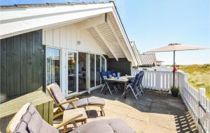 een patio met stoelen, een tafel en een parasol bij 3 Bedroom Awesome Home In Rm in Havneby