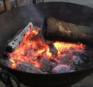 a large grill with meat and fire in it at Holly Cottage The Studio in Sambrook