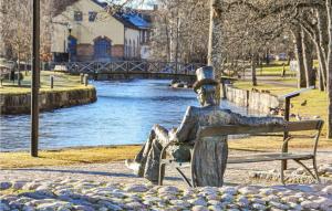 une statue d'un homme assis sur un banc à côté d'une rivière dans l'établissement Beautiful Home In Filipstad With Kitchen, à Filipstad