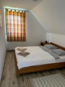 een slaapkamer met een bed met witte lakens en een raam bij Hillside Apartments in Révfülöp