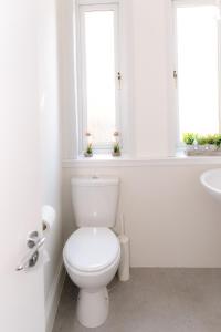 La salle de bains blanche est pourvue de toilettes et d'un lavabo. dans l'établissement GreenStar Apartments, à Dundee