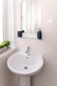 a bathroom with a white sink and a mirror at GreenStar Apartments in Dundee