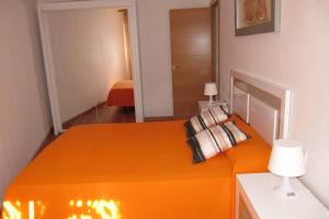 1 dormitorio con 1 cama con sábanas y almohadas de color naranja en piso con estilo cerca de la playa, en Cullera