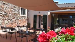 eine Terrasse mit Tischen, Stühlen und roten Blumen in der Unterkunft L'Iris B&B in Terrazza in Lucca