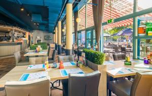 un ristorante con tavoli e sedie in legno e finestre di Sunset Beach House a L'Aia