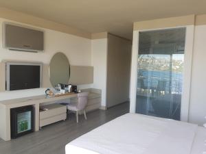 a bedroom with a bed and a desk and a mirror at Bilkent Casa Costa Hotel in Gundogan