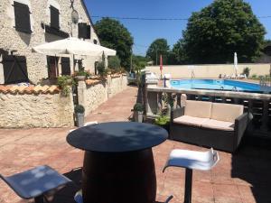 patio ze stołem i krzesłami oraz basenem w obiekcie LES GRANGES w mieście Les Lèves-et-Thoumeyragues