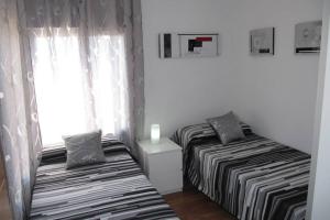 two beds in a small room with a window at piso con estilo cerca de la playa in Cullera