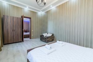 a bedroom with a large bed and a chair at White Hotel Guesthouse in Zugdidi