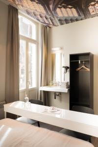 Cette chambre comprend une table blanche, des chaises et des fenêtres. dans l'établissement Hotel Marcel, à Bruges