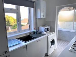 a kitchen with a sink and a washing machine at Luxury Suntrap in Private Complex St Leonards in Hastings +11 photos
