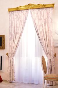 a window with a white curtain and a chair at Palazzo Castiglione Dimora Storica in Gallipoli