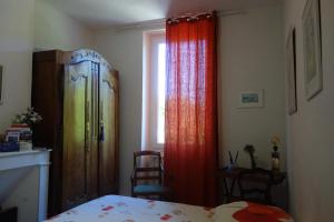a bedroom with a bed and curtains and a window at La Maison sur la Colline in Mauroux