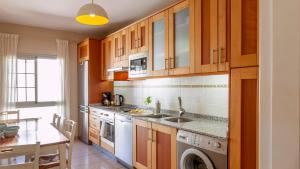 a kitchen with wooden cabinets and a sink and a dishwasher at Maxorata in Morro del Jable