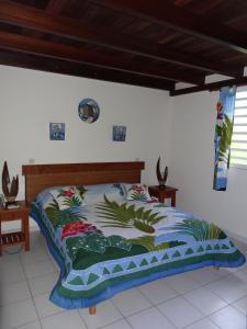 1 dormitorio con 1 cama con un edredón colorido en Résidence des îles, en Le Marin