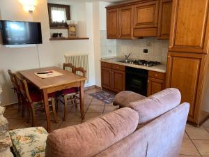 sala de estar con sofá y cocina con mesa en Appartamenti da Clara, en La Thuile
