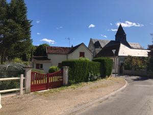 una casa con una recinzione rossa sul lato di una strada di Le gite du Canal a Noyers-sur-Cher