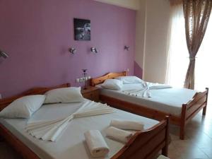 two twin beds in a room with pink walls at Poseidon rooms in Nea Vrasna +27 photos