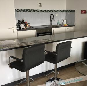 a kitchen with two black chairs and a sink at Fewo Nationalpark Schwarzwald in Freudenstadt