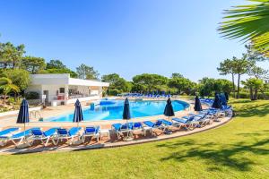 a large swimming pool with chairs and umbrellas at Victory Village T1 & Rooftop terrace in Quinta do Lago