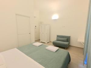 een slaapkamer met een bed en een groene stoel bij Central Savona B&B in Savona