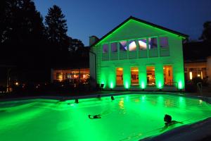 ein Schwimmbad mit grünen Lichtern vor einem Gebäude in der Unterkunft Hotel Eifelsteig in Roetgen