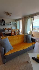 a large yellow couch in a living room with a table at GRAND CAP Appartement 2 chambres vue mer in Saint-Jean-de-Monts