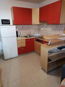 a kitchen with red cabinets and a white refrigerator at Meje Apartments in Split