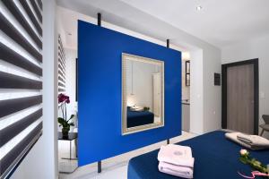 een kamer met een blauwe muur en een spiegel bij Adell Deluxe Apartments in Kavala