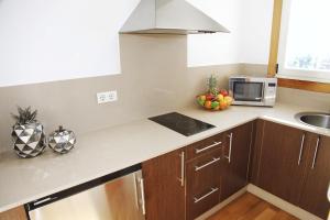 a kitchen with a sink, stove, microwave and cabinets at Augusta Eco Wellness Resort in Sanxenxo