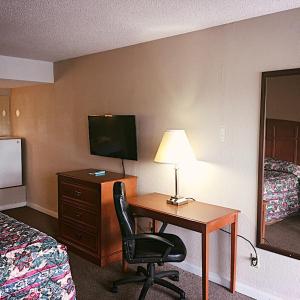 a hotel room with a desk with a lamp and a chair at Travelers Inn Elizabethton in Elizabethton