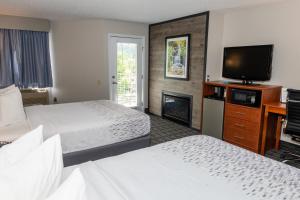 um quarto de hotel com duas camas e uma televisão de ecrã plano em Twin Mountain Inn & Suites em Pigeon Forge