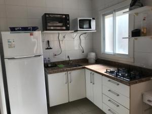 a kitchen with a white refrigerator and a microwave at Ed Gustavo in Capão da Canoa