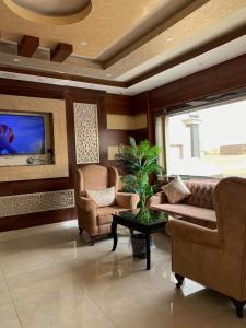 a living room with a couch and chairs and a tv at Alshahamah Hotel Apartments in Najran