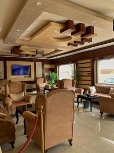 uma sala de estar com cadeiras, um sofá e mesas em Alshahamah Hotel Apartments em Najran