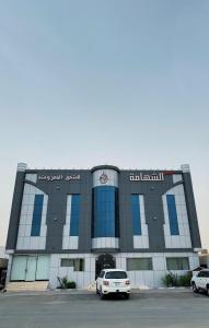 a building with two cars parked in a parking lot at Alshahamah Hotel Apartments in Najran