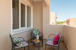 Altré Guest House في أولبيا: كرسيين وطاولة على شرفة مع نافذة