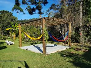 a hammock in a wooden frame in a garden at Pousada Beira rio in Visconde De Maua