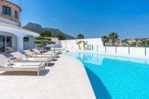 a swimming pool with lounge chairs next to a building at Maryvilla Inspiracion y Vacaciones - Grand Villa Penon in Calpe