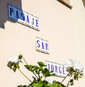 dos letreros en una pared con una planta en Pasaje San Jorge en Comillas