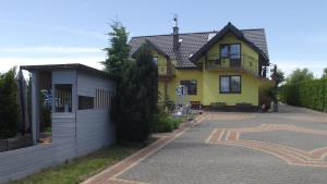 a yellow house with a driveway in front of it at Pokoje typu Studio OLSZYNA in Ustronie Morskie