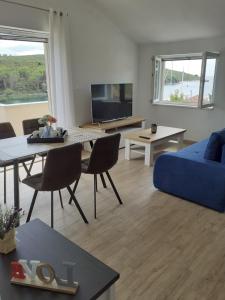 uma sala de estar com um sofá azul e uma mesa em Apartmani Goga 2 em Molat